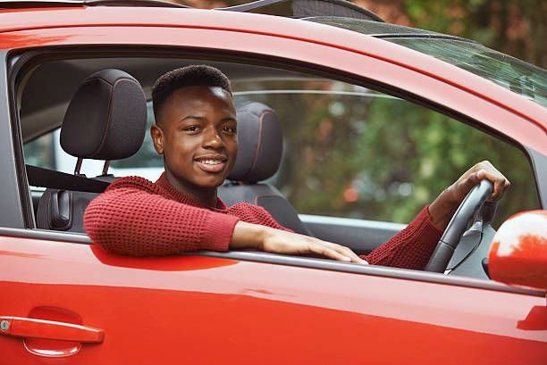 Young teen driver smiling while driving a red car during DMV test
