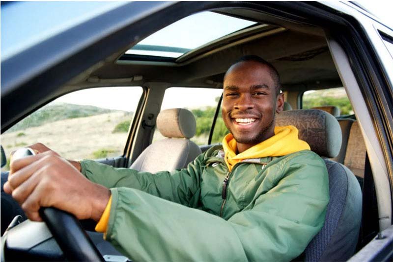Happy California teen driver smiling while driving on a sunny day