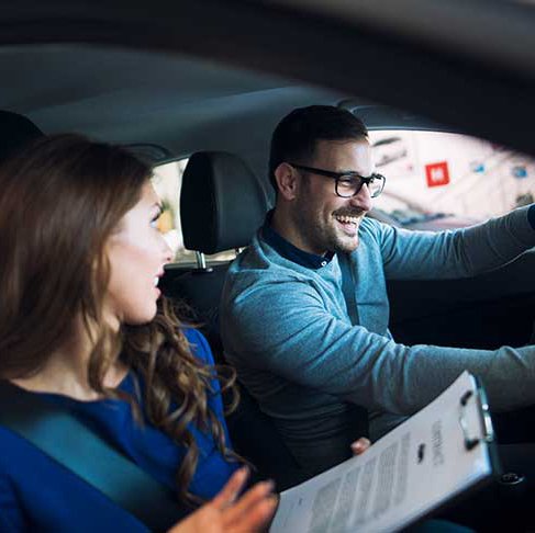 Young couple smiling in a car during driving lesson